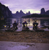 Three fishermen on bamboo boats at dusk